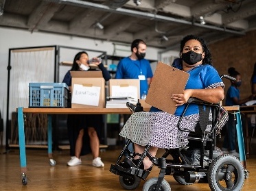 Someone holding a clipboard in front of 2 other people who are collecting information in boxes.