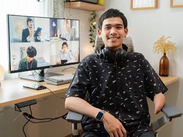 A person with disability working from home. Their computer screen shows people on a video call.
