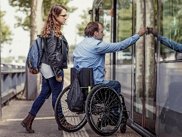 2 people using public transport. One person is using a wheelchair.