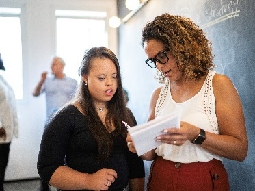 2 people looking at a document together in a classroom.