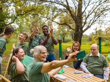 A community group with a diverse group of people taking a photo together at a picnic table.