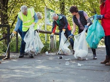 A group of people picking up rubbing in a park.